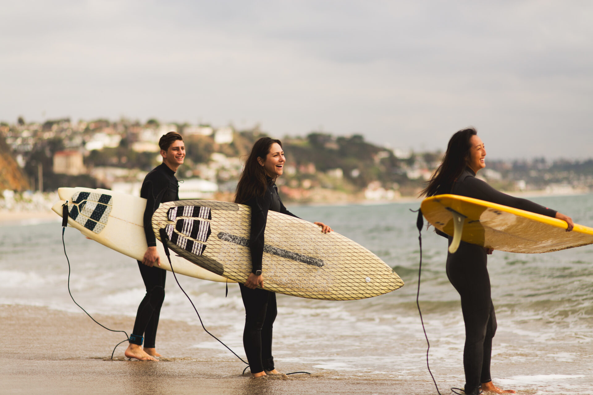 Three friends standing in sea, holding surfboards, preparing to surf Surfin